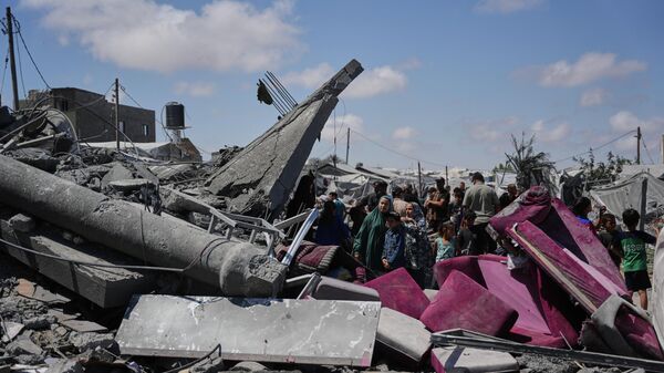 فلسطينيون يتفقدون أنقاض مبنى دُمّر جراء غارة جوية إسرائيلية في خان يونس، جنوبي قطاع غزة. - سبوتنيك عربي