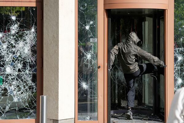 صورة تظهر أحد المتظاهرين وهو يركل  نافذة خلال مظاهرة "لا لمجموعة السبع" في جنيف، سويسرا، قبيل انعقاد قمة مجموعة السبع المقرر عقدها في الفترة من 15 إلى 17 يونيو/حزيران. - سبوتنيك عربي