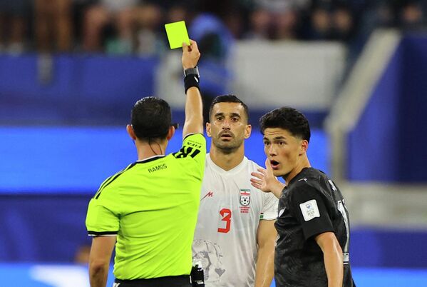 لحظة قيام الحكم، سيزار أرتورو راموس، بإشهار البطاقة الصفراء في وجه اللاعب الإيراني، إحسان حاج‌ صفي، بعد ارتكابه مخالفة خلال مباراة إيران ونيوزيلندا في كأس العالم 2026. - سبوتنيك عربي