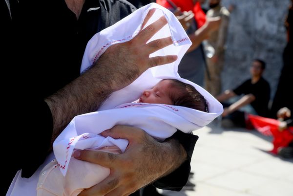 يقف رجل برفقة طفل في ساحة قرب مسجد الإمام الخميني في طهران، حيث تُقام مراسم وداع رسمية للمرشد الأعلى الإيراني الراحل علي خامنئي وأفراد أسرته. - سبوتنيك عربي
