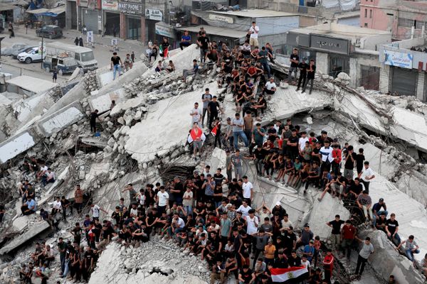 صورة تظهر تجمع فلسطينيين لمشاهدة مباراة دور الـ16 من بطولة كأس العالم لكرة القدم 2026 بين الأرجنتين ومصر، على شاشة في مدينة غزة، وسط الركام الموجود في أرجاء المكان. - سبوتنيك عربي