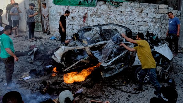 فلسطينيون يحاولون إخماد سيارة مشتعلة بعد غارة عسكرية إسرائيلية في مدينة غزة. - سبوتنيك عربي