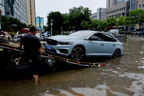 عامل يُحمّل سيارة معطلة على شاحنة نقل سيارات في شارع غمرته المياه بعد أن جلب إعصار دولفين أمطارًا غزيرة إلى شنغهاي، الصين، ١٠ أغسطس/آب ٢٠٢٦. (رويترز/جو ناكامورا). - سبوتنيك عربي