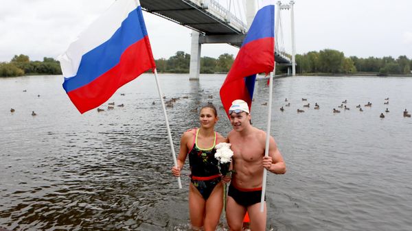 Мастера спорта России по плаванию Есения Ларионова и Кирилл Василовский после 6-километрового эстафетного заплыва по Енисею, посвящённого Дню государственного флага России, Красноярске - سبوتنيك عربي