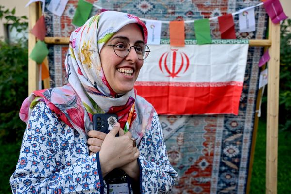 صورة تظهر إحدى المشاركات في مهرجان الشباب العالمي، ويظهر في الخلف علم الجمهورية الإسلامية الإيرانية.  - سبوتنيك عربي