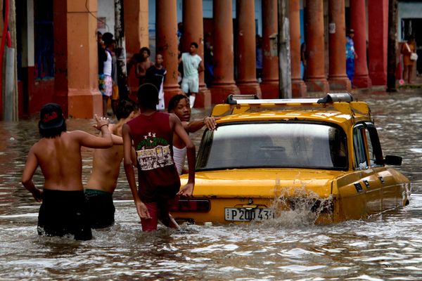 أشخاص يدفعون سيارة وسط مياه الفيضانات عقب هطول أمطار غزيرة في هافانا، الأربعاء، 23 سبتمبر/أيلول 2026. - سبوتنيك عربي