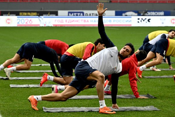 مجموعة من لاعبي المنتخب الإيراني يؤدون تمارين إطالة وتمارين مرونة على العشب، حيث يظهر اللاعبون بوضعيات الانحناء. - سبوتنيك عربي