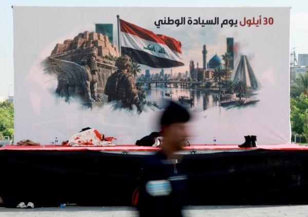 شخص يسير بجوار منصة تحمل لافتة بمناسبة "يوم السيادة" في بغداد - سبوتنيك عربي