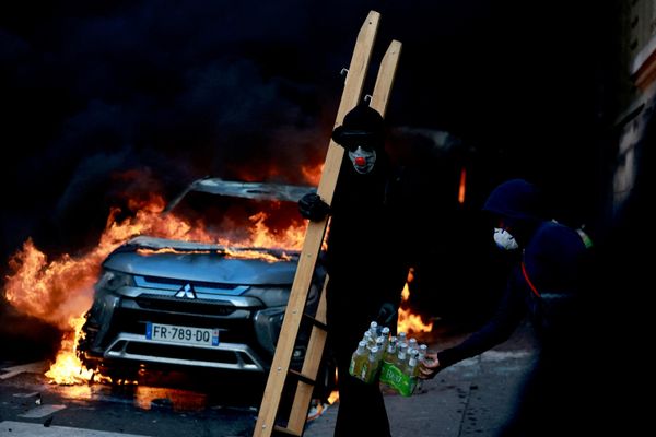 متظاهر ملثم يمر بجوار سيارة مشتعلة وسط اشتباكات خلال مظاهرة احتجاجا على غلاء المعيشة وارتفاع أسعار الوقود بالقرب من ساحة الجمهورية في باريس. - سبوتنيك عربي