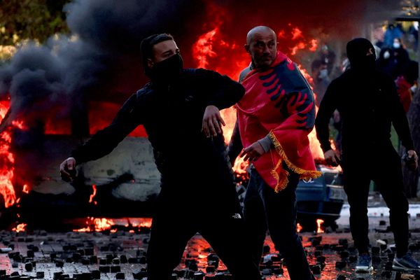 متظاهر يغطي نفسه بالعلم الوطني الألباني خلال اشتباكات بين محتجين والشرطة في تيرانا، ألبانيا. - سبوتنيك عربي