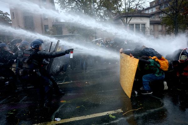 متظاهرون يحتمون خلف لوح من الخشب أثناء قيام قوات مكافحة الشغب والدرك الفرنسي برشهم بواسطة خراطيم المياه، وذلك وسط اشتباكات اندلعت خلال مظاهرة مرخص لها  في باريس. - سبوتنيك عربي