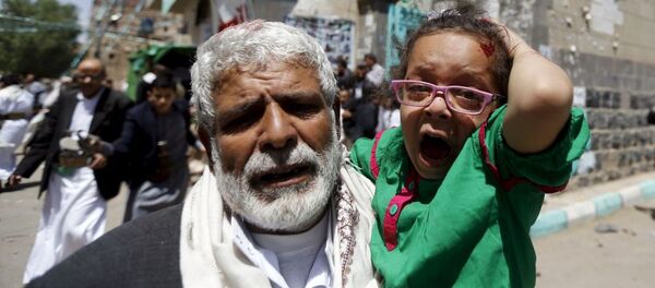 رجل مسن يهرب بطفلة من مكان الانفجار في اليمن اليوم الجمعة 20 مارس/ آذار 2015. - سبوتنيك عربي