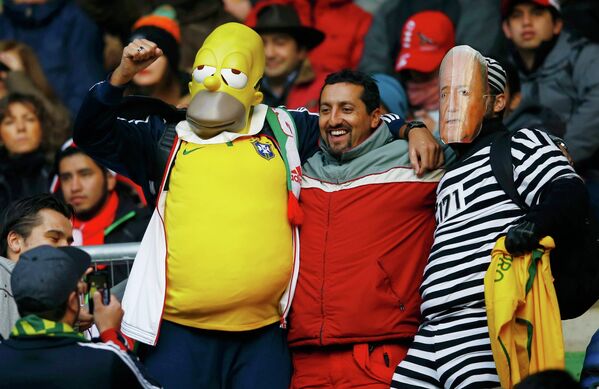 من داخل مدرجات البرازيل، مشجع يرتدى قناع سيمبسون وأخر يرتدى قناع بلاتر رئيس الفيفا، قبل انطلاق مباراة منتخب بلادهم أمام بيرو فى اطار الجولة الأولى على ملعب البلدية، شيلي، 14 يونيو  2015. - سبوتنيك عربي