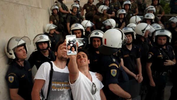يونانيون يأخذون السليفى مع قوات الأمن خلال مسيرة إحتجاجية ضد الإتحاد الأوروبي أمام البرلمان اليوناني - سبوتنيك عربي