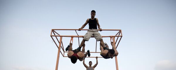 عدد من الشباب الفلسطيني يمارس تمارين رياضية في أحد الشوارع على ساحل البحر في غزة - سبوتنيك عربي