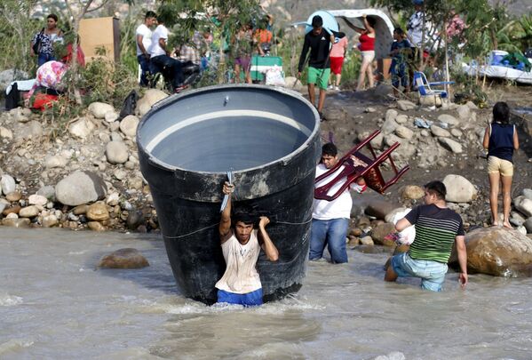 ناس ينقلون أمتعتهم عبر النهر على الحدود بين فنزويلا وكولومبيا - سبوتنيك عربي