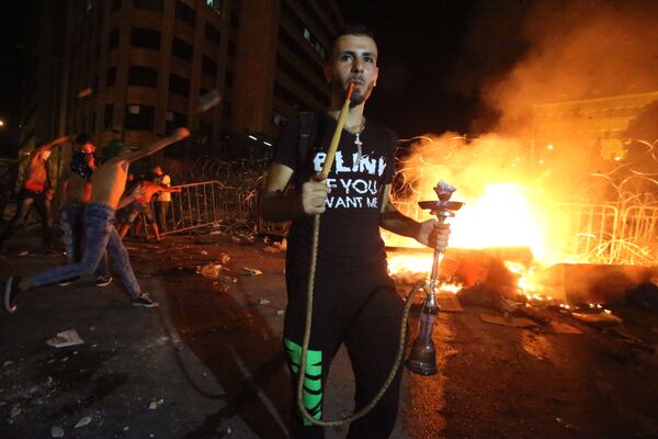 متظاهر لبناني يدخن الأركيلة (الشيشة) أثناء اشتباكات مع قوات الأمن - سبوتنيك عربي