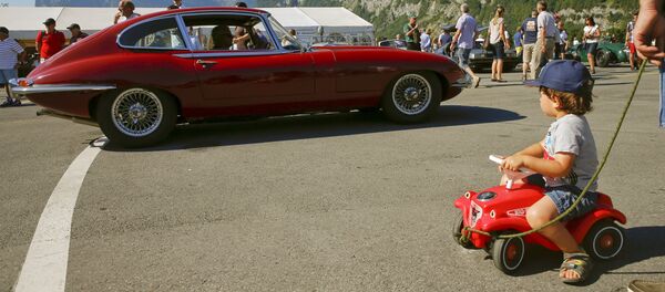 صبي ينظر إلى سيارة جاكوار– نوع E  أثناء معرض للسيارات البريطانية القديمة في قرية موليس، شرق زيوريخ.  - سبوتنيك عربي