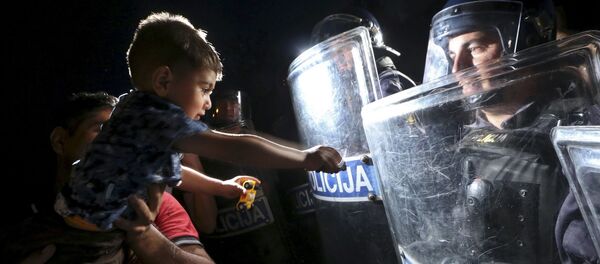 طفل يمد يده إلى درع الشرطي في كرواتيا - سبوتنيك عربي