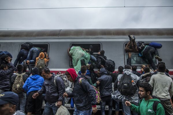 المهاجرون يحاولن الصعود الى القطار من خلال النوافذ، كرواتيا - سبوتنيك عربي