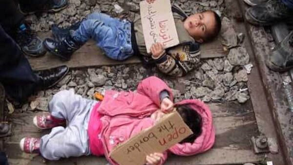 لاجئون يضعون أطفالهم على سكة القطار مع لافتات كتب عليها افتحوا الحدود - سبوتنيك عربي
