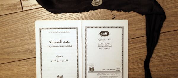 A suicide bomber's head-band and a manual, entitled “How to wage an ideal fight against the criminal Assad regime” found in an office of one of the Daesh jihadists in Shadadi. - سبوتنيك عربي