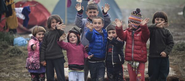أطفال اللاجئين يلوحون بأيديهم الصغيرة للمصور، الحدود اليونانية، 18 مارس/ آذار 2016. - سبوتنيك عربي