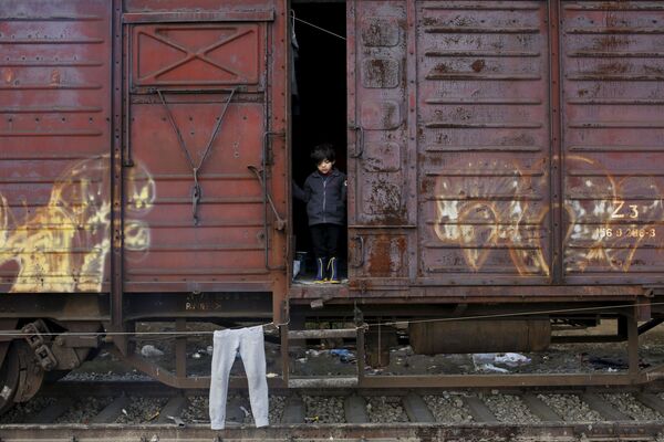 طفل لاجئ ينظر من خارج قطار في مخيم للاجئين على الحدود المقدونية-اليونانية، 28 مارس/ آذار 2016. - سبوتنيك عربي