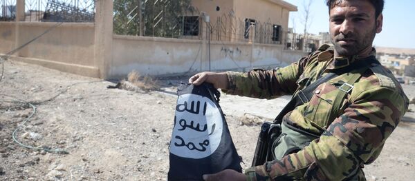 جندي من الجيش العربي السوري يحمل علم تنظيم داعش في مدينة القريتين، وذلك بعد تحريرها من التنظيم. - سبوتنيك عربي