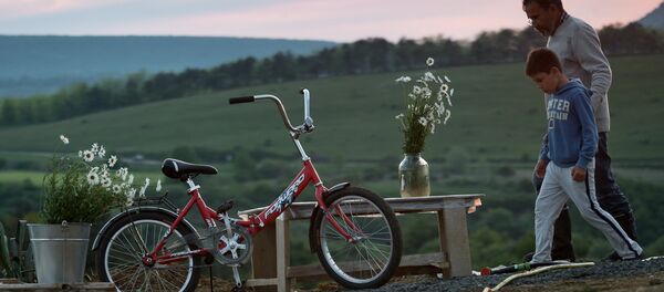 رجل وطفل يسيران في قرية كلينكوفا بسيمفيروبل، شبه جزيرة القرم. - سبوتنيك عربي