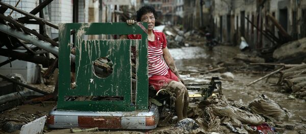 امرأة تجلس وسط شارع في الصين بعد طوفان ضرب البلاد، 10 يوليو/ تموز 2016. - سبوتنيك عربي