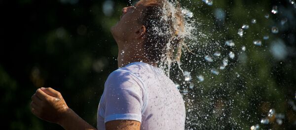 رجل يهرب من حر الجو إلى نافورة المياه زافيسا على ساحة مانيجنايا في موسكو - سبوتنيك عربي