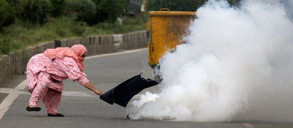 امرأة تحاول ابعاد قنبلة غاز مسيل للدموع خلال التصادمات مع الشرطة في كشمير، 17 أغسطس/ آب 2016 - سبوتنيك عربي