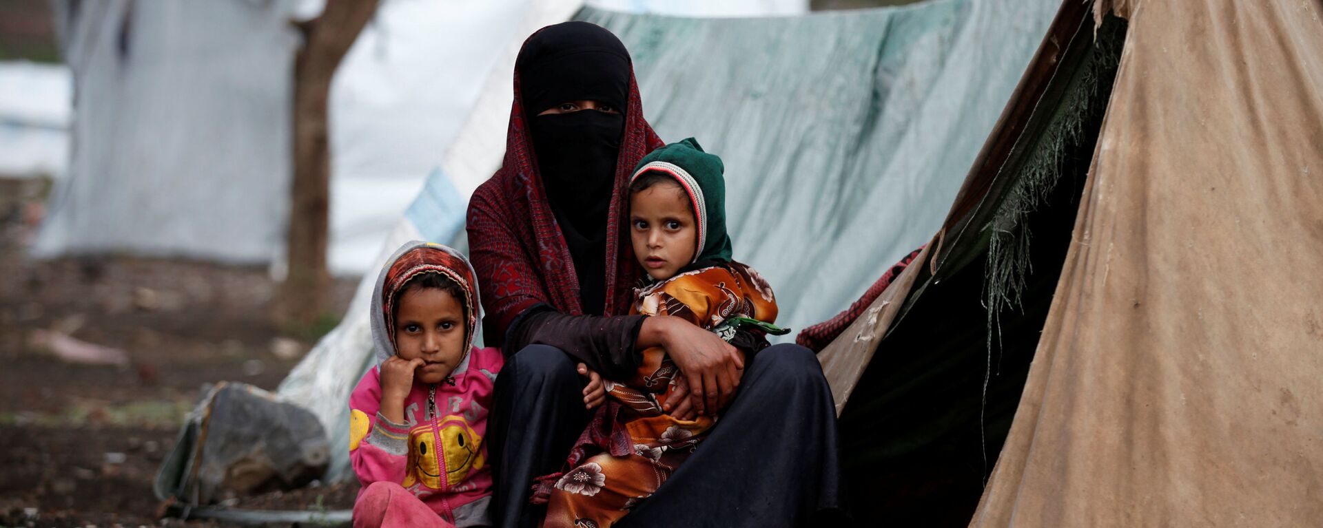 امرأة مع طفلتيها تجلس قبالة خيمتها بمخيم للنازحين في أحد شوارع مدينة صنعاء، اليمن 15 أغسطس/ آب 2016 - سبوتنيك عربي, 1920, 01.04.2022