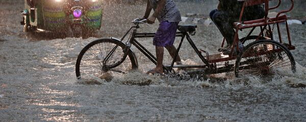 رجل يجر عربة النقل خلال أمطار غزيرة في مدينة نيودلهي، الهند 31 أغسطس/ آب 2016 - سبوتنيك عربي
