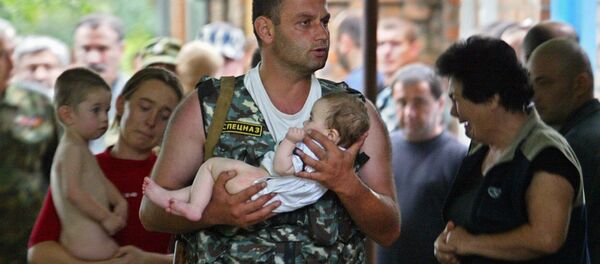 جندي من وحدة القوات الخاصة الروسي يحمل طفلاً، كان رهينة بمدرسة في بيسلان، أوسيتيا الشمالية - سبوتنيك عربي