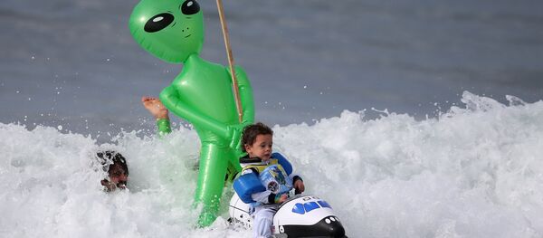 طفل يرتدي زياً لرائد فضاء خلال ركوب الأمواج خلال مهرجان الهالووين في سان مونيكا، كاليفورنيا 29 أكتوبر/ تشرين الأول 2016 - سبوتنيك عربي