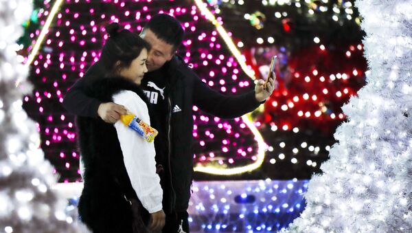 حبيبان، رجل وامرأة يلتقطان صورة سيلفي على خلفية أضواء أعياد رأس السنة في بكين، 1 ديسمبر/ كانون الأول 2016 - سبوتنيك عربي
