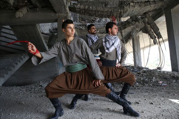 شبان من فرقة النشامة يؤدون رقص الدبكة داخل مبنى دُمّر في الحرب الأخيرة على قطاع غزة، 7 ديسمبر/ كانون الأول 2016 - سبوتنيك عربي