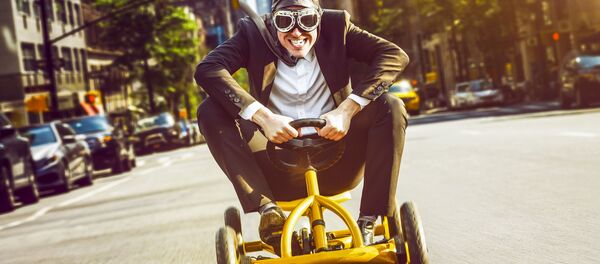 Мужчина в очках и шлеме пилота на детском автомобиле - سبوتنيك عربي