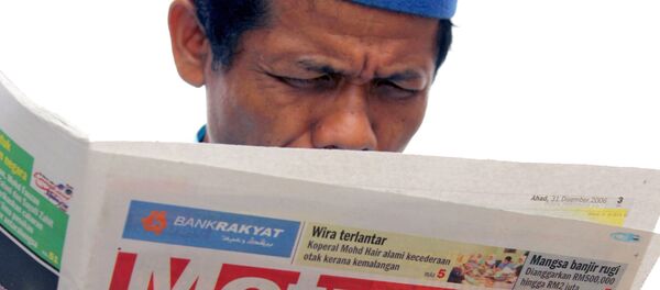 رجل يقرأ نبأ إعدام الرئيس العراقي السابق صدام حسين في كوالا لمبور، 31 ديسمبر/ كانون الأول 2006 - سبوتنيك عربي