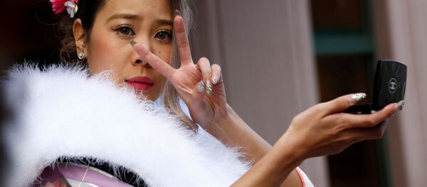 فتاة يابانية ترتدي الزي التقليدي الياباني كيمونو تمسك بمرأتها وتعدّل على المكياج، اليابان 9 يناير/ كانون الثاني 2017 - سبوتنيك عربي