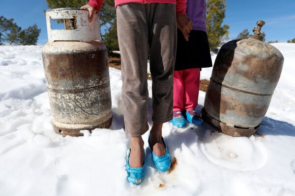 إيمان (9 أعوام) ونورا (5 أعوام) تقفان بجانب أنابيب غاز خلال انتظارهما لشاحنة الغاز لأخذها، جبال الأطلس الصحراوي بالجزائر 26 يناير/ كانون الثاني 2017 - سبوتنيك عربي