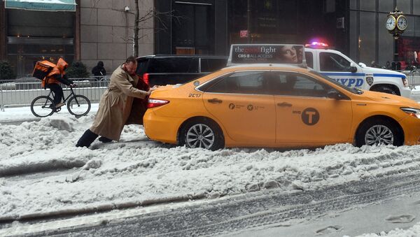 راكب سيارة أجرة في مدينة نيويورك يحاول دفع السيارة من مكانها، نيويورك 14 مارس/ آذار 2017 - سبوتنيك عربي