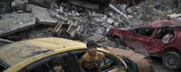 أطفال يلعبون داخل سيارة دمرت خلال المواجهات الحامية التي دارت بين قوات الأمن العراقية وتنظيم داعش في الجانب الغربي من الموصل، العراق 1 أبريل/ نيسان 2017 - سبوتنيك عربي