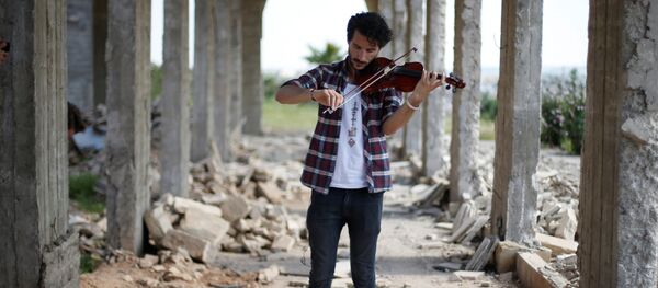 أمين مقداد يعزف على الكمان وسط ركام المباني في شرق مدينة الموصل، وذلك بعد أن كانت واقعة تحت سيطرة تنظيم داعش الإرهابي لمدة تزيد عن عامين ونصف، العراق 19 أبريل/ نيسان 2017 - سبوتنيك عربي