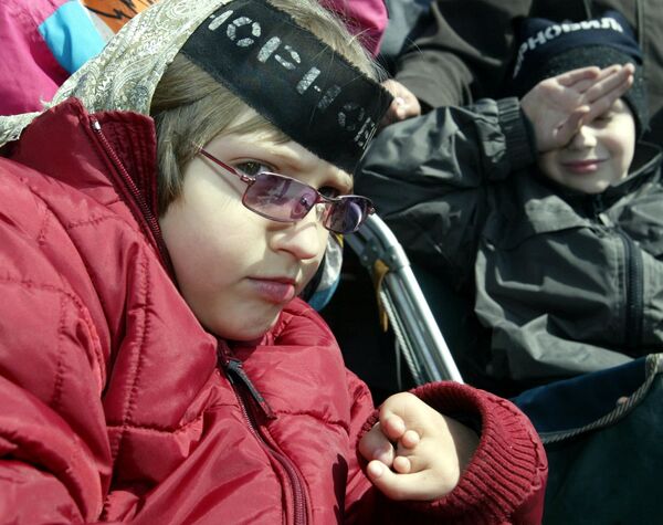 كارثة تشيرنوبيل - طفلة تضع اشارة سوداء تشيرنوبيل، ولدت مصابة بالإعاقة بعد الكارثة - سبوتنيك عربي