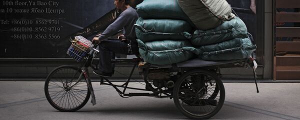 رجل يركب دراجة هوائية على خلفية إعلان للمركز التجاري ريتان الدولي في بكين، الصين 8 مايو/ آيار 2017 - سبوتنيك عربي