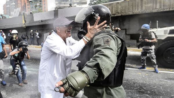 أحد المعارضين يجادل شرطي منالحرس الأمن القومي خلال الاحتجاجت في العاصمة كاراكاس، فنزويلا 22 مايو/ آيار 2017 - سبوتنيك عربي