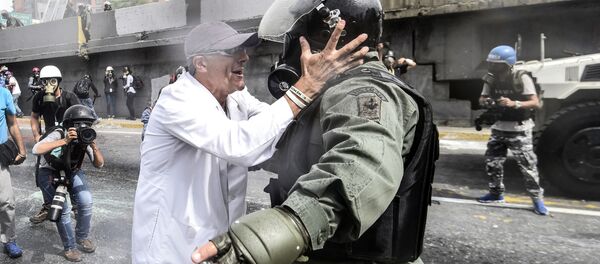 أحد المعارضين يجادل شرطي منالحرس الأمن القومي خلال الاحتجاجت في العاصمة كاراكاس، فنزويلا 22 مايو/ آيار 2017 - سبوتنيك عربي